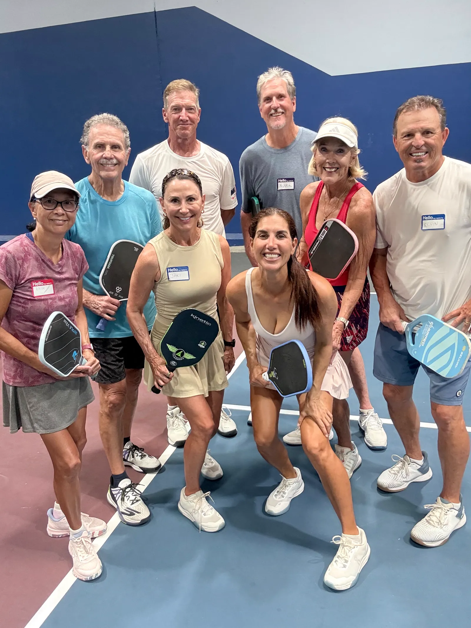 Jen with a group of clinic players wearing name tags on an indoor court