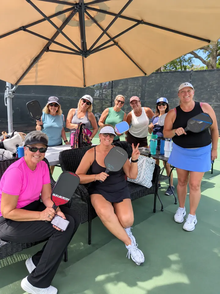 Players gathering courtside under a shade umbrella before play